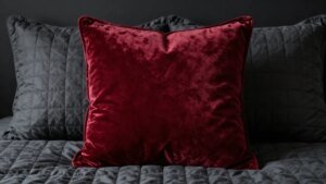 Velvet oxblood pillow detail against charcoal quilt in moody bedroom scene